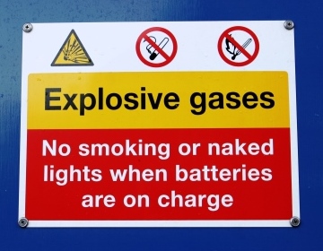 A hazard identification sign which reads: 'Explosive gases - No smoking or naked lights when batteries are on charge'